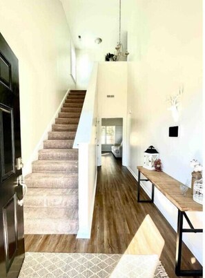 Staircase leads to an upper level with a carpeted design and a wooden bench.