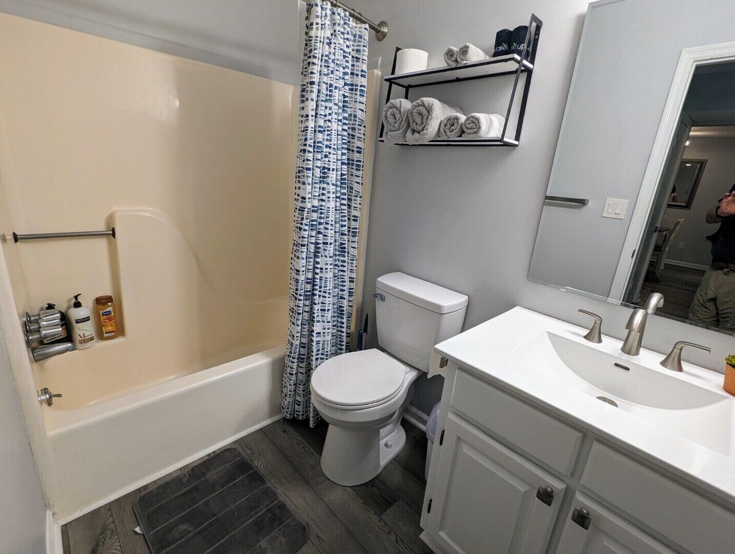 Un baño con bañera, inodoro y tocador con lavabo.