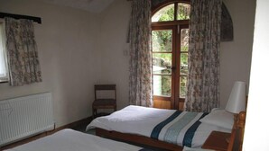 A room with two beds, a chair, a window with curtains, and a radiator. - Beautiful Large Rural Cottage Near Pencader (Pencader)