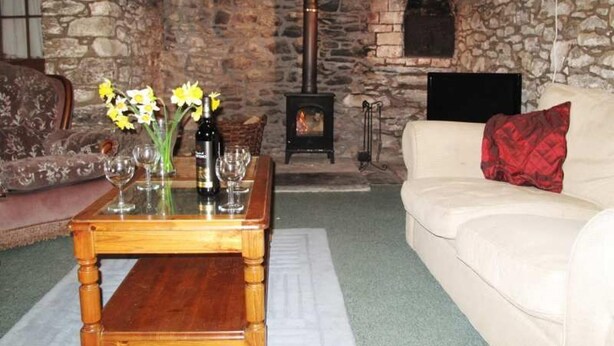 A cozy living room with a stone fireplace, a wooden coffee table with flowers, and a white sofa. - Beautiful Large Rural Cottage Near Pencader (Pencader)