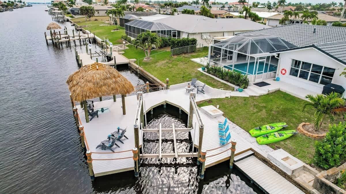 A waterfront property with a dock, a swimming pool, and a covered outdoor area.