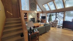 A spacious living area with a fireplace, a large window, and a staircase. - Fox'em Falls (Roseland)