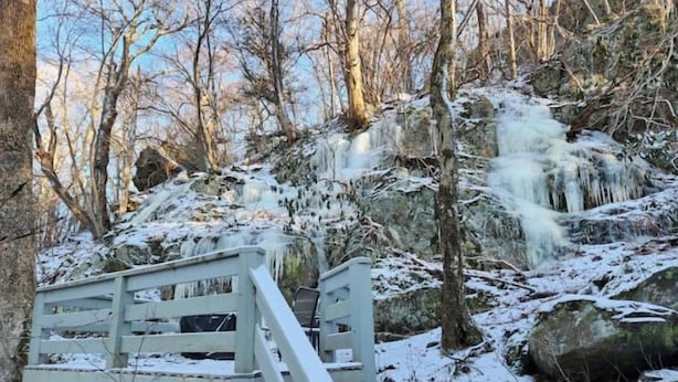A wooden staircase leading up to a rocky area with a small wooden platform and a bench. - Fox'em Falls (Roseland)