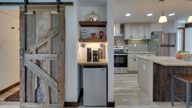 Una cocina con puerta de madera, electrodomésticos de acero inoxidable y encimera de granito.