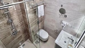 A modern bathroom with a glass shower enclosure, a toilet, and a sink with a mirror. - Petra Icon Hotel (Wadi Musa)