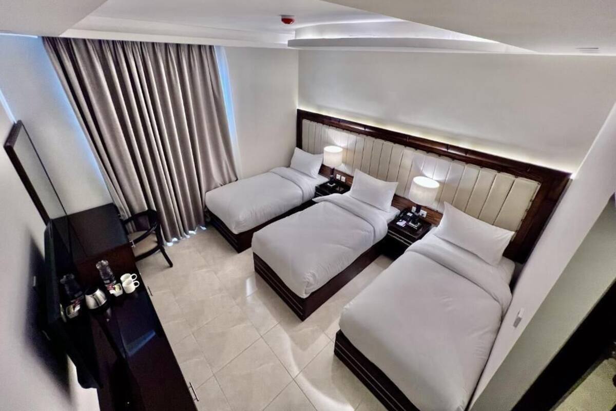 A hotel room with two beds, a desk, and a chair.