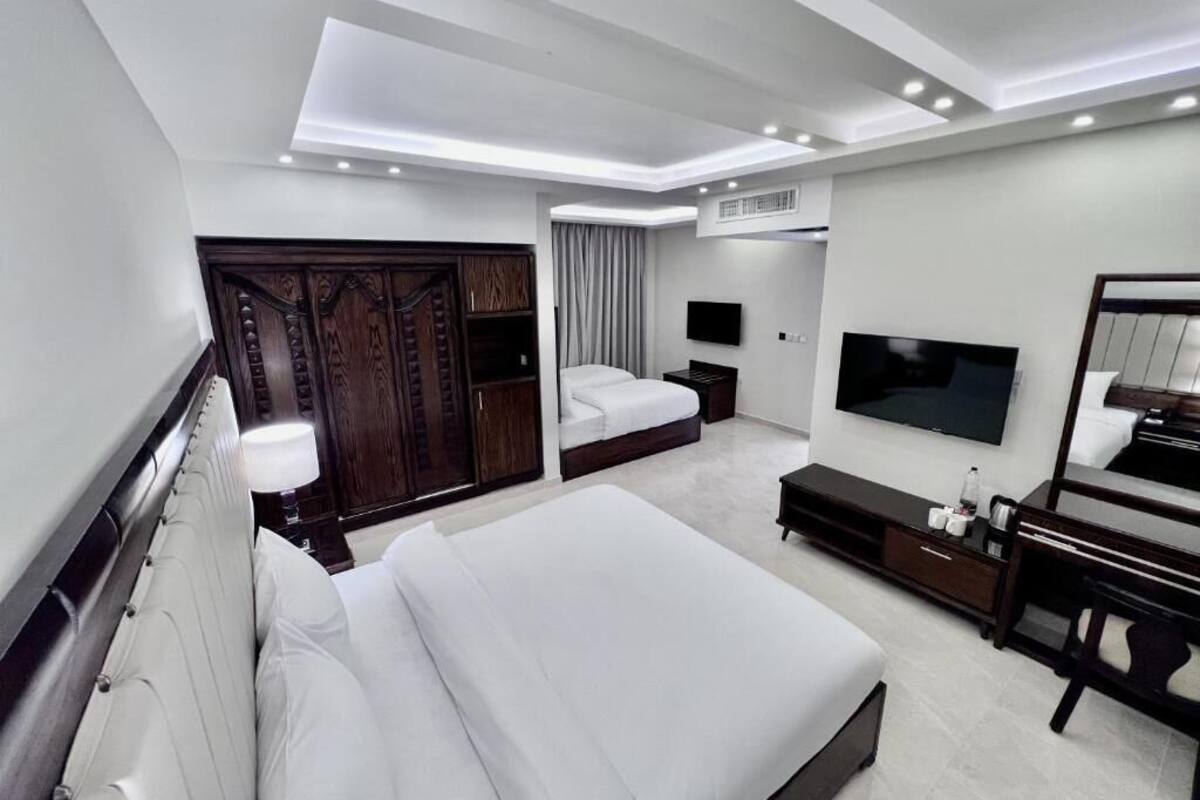 A modern hotel room with a large bed, a TV, a wardrobe, and a mirror.
