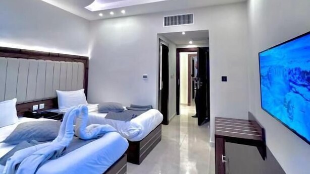 A modern hotel room with a large bed, a flat-screen TV, and a bathroom visible through an open door. - Petra Icon Hotel (Wadi Musa)