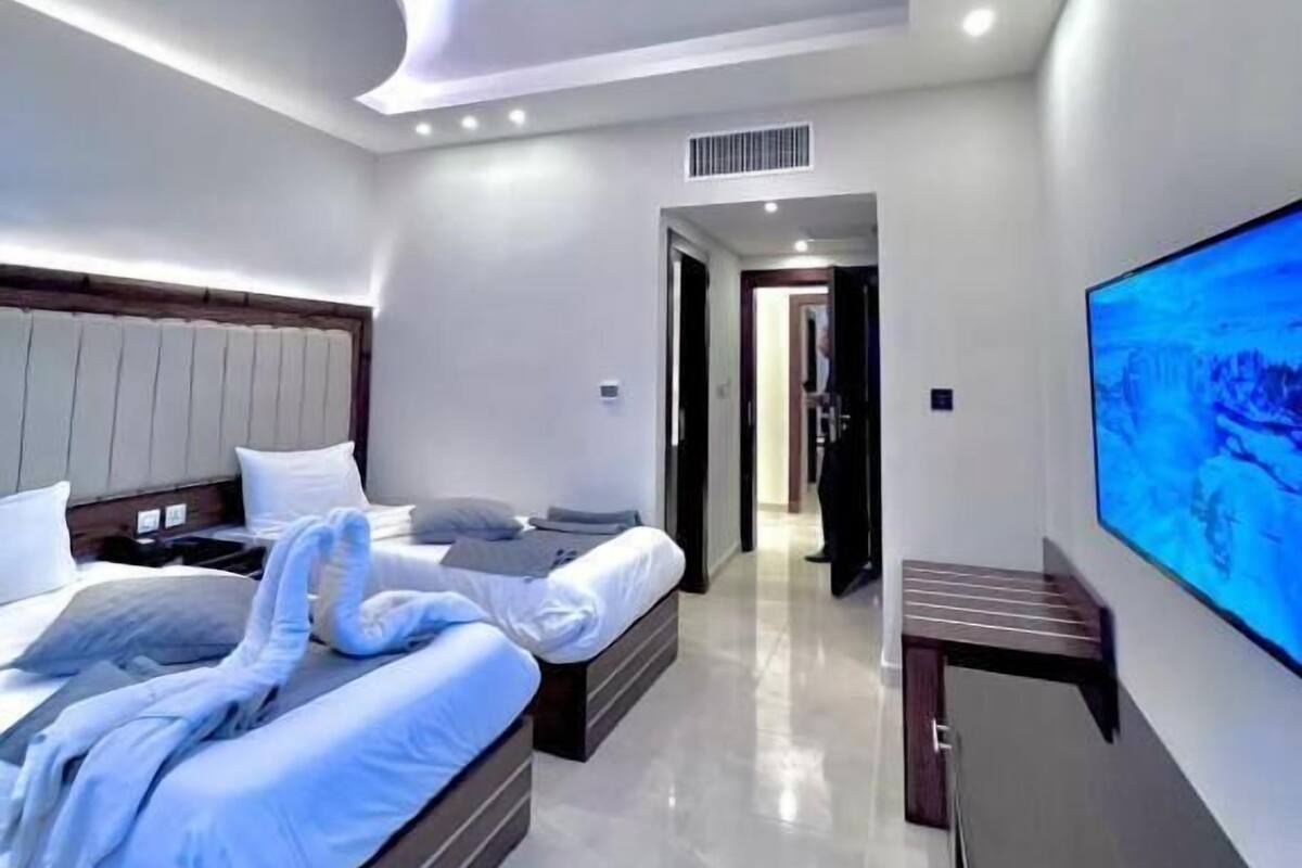 A modern hotel room with a large bed, a flat-screen TV, and a bathroom visible through an open door.