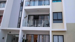 A multi-story building with balconies, a bicycle parked outside, and a clear sky.