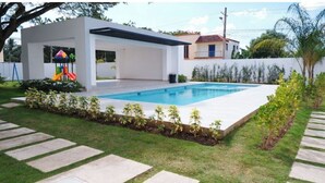 A modern house with a swimming pool, a covered patio, and a small children's play area.