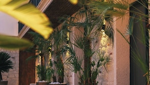 A covered outdoor seating area with potted plants and wooden chairs. - Rupa Experience Alacati (Cesme)