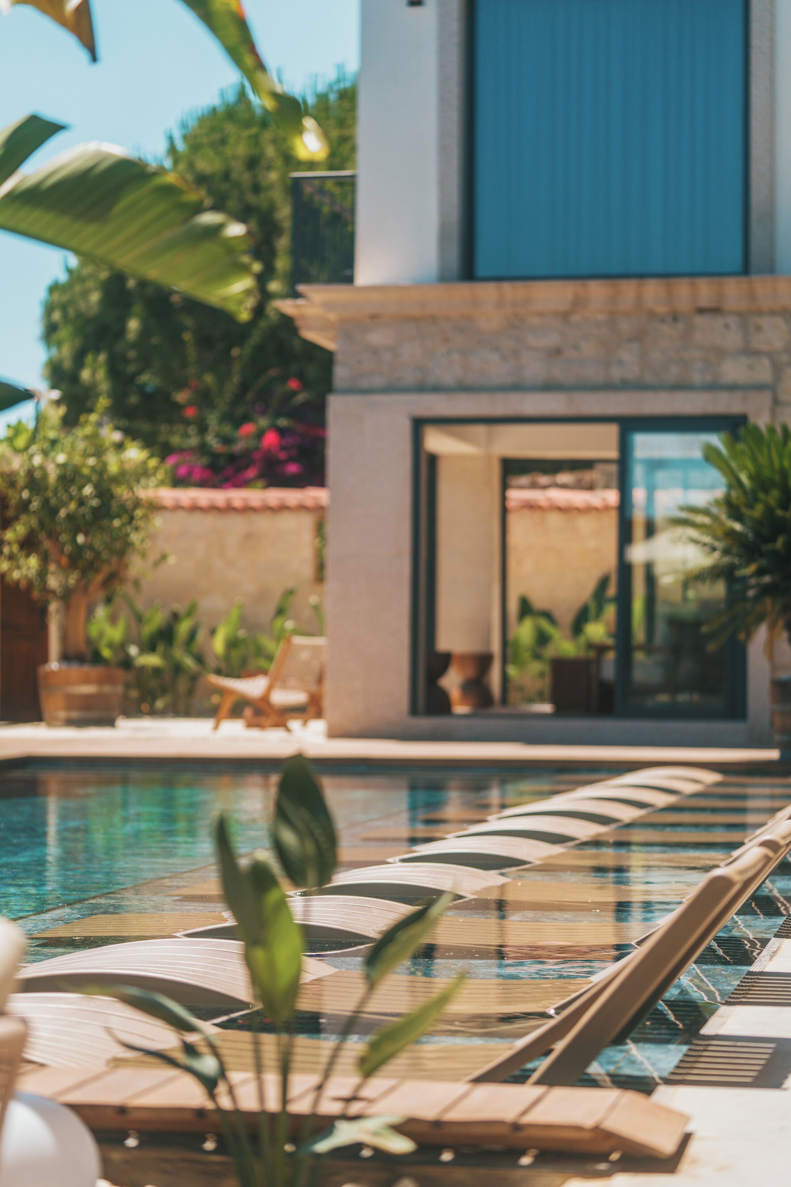 A swimming pool with lounge chairs and potted plants.