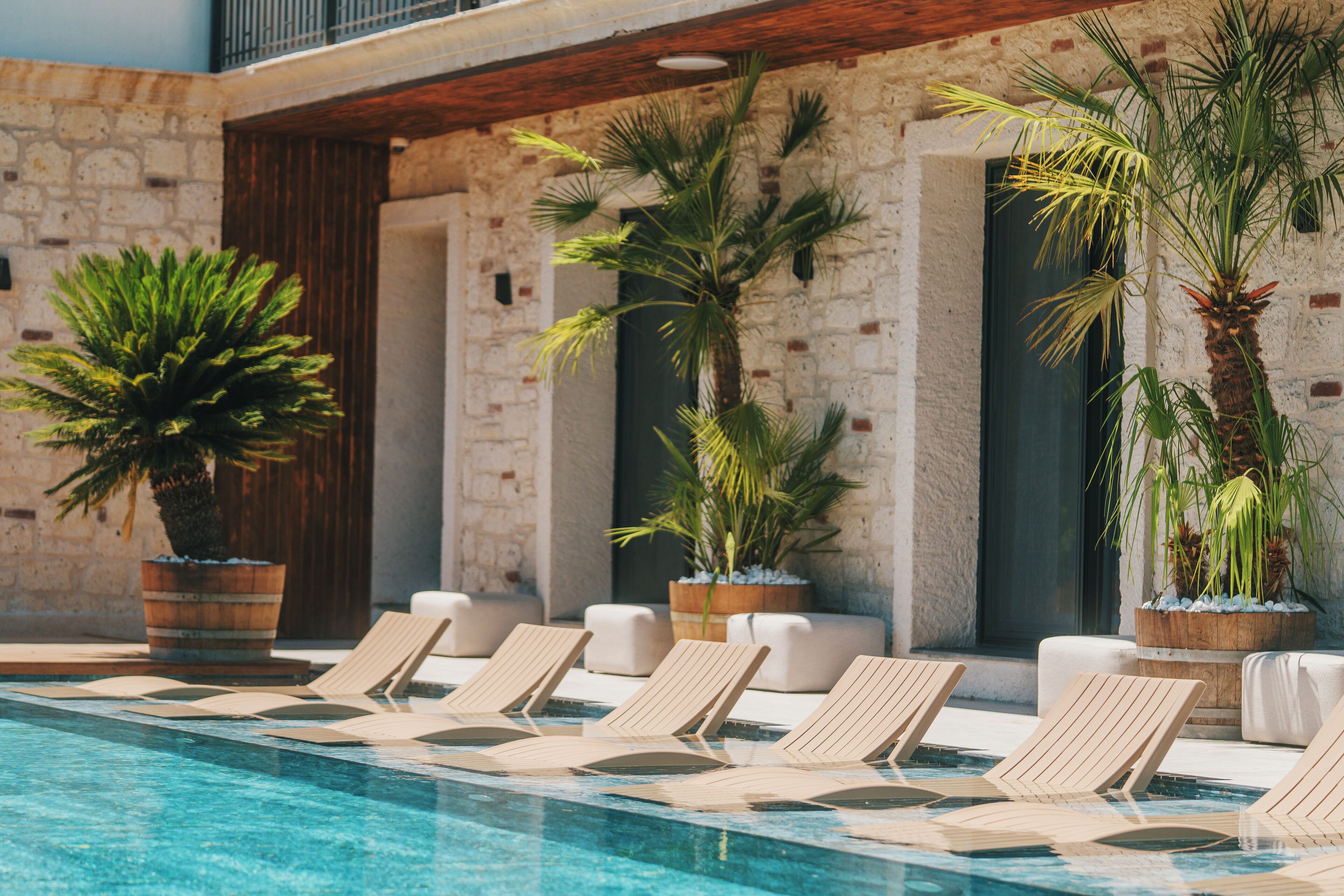 A poolside area with lounge chairs and potted plants.