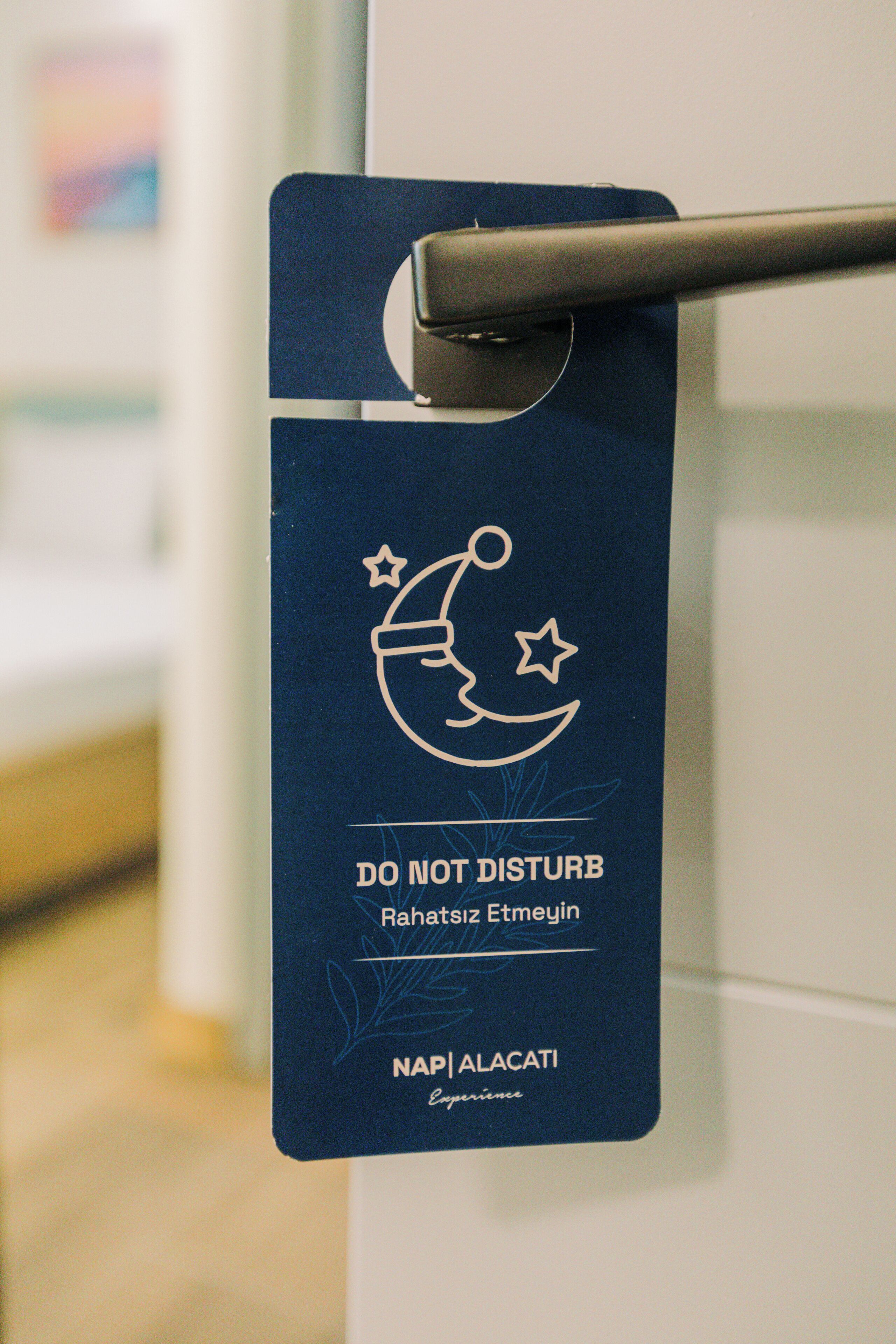 A door with a blue sign that reads "DO NOT DISTURB" and "Rahatiz Etmezin" along with "NAP | ALACATI" and "Experience".