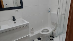 Un baño con lavamanos blanco, inodoro y cabina de ducha.