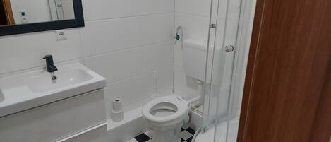 Un baño con lavamanos blanco, inodoro y cabina de ducha.