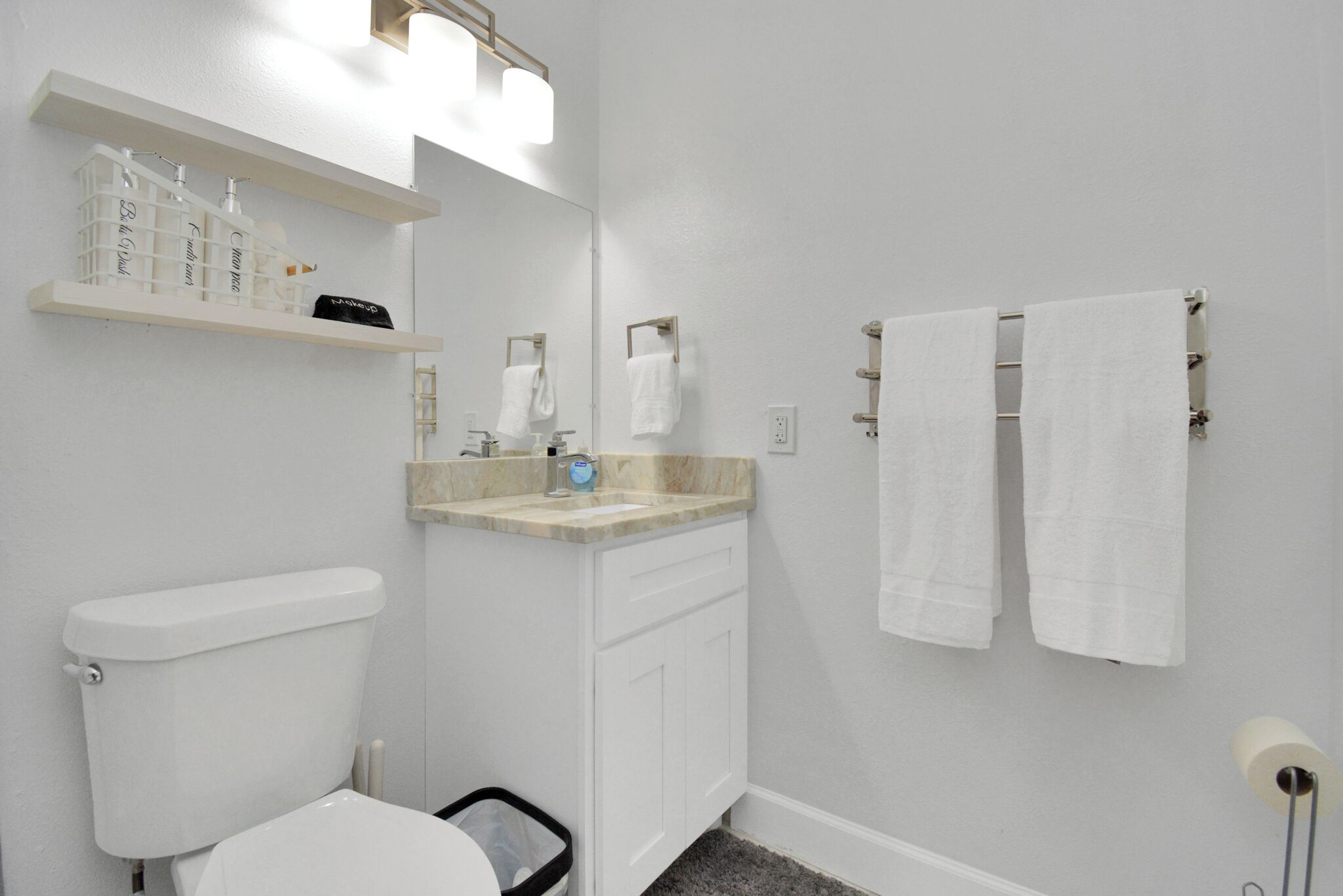 Une salle de bain équipée de toilettes, d’un lavabo et d’un porte-serviettes.