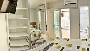 Una habitación de hotel con cama, armario, baño y balcón.