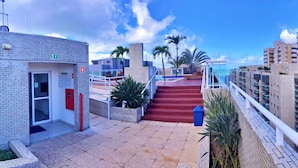 Un edificio con una escalera roja que lleva a un balcón con palmeras.