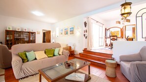 A living room with a beige sofa, a glass coffee table, and a wooden cabinet. - Xodo - CHARMING AND SECLUDED THREE-BEDROOM VILLA (Carvoeiro)
