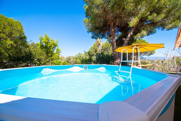A swimming pool with a ladder, surrounded by trees and a clear sky. - Xodo - CHARMING AND SECLUDED THREE-BEDROOM VILLA (Carvoeiro)