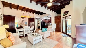 A spacious living area with a dining table, white sofas, a coffee table, and a kitchen in the background. - Mission Gate 5B @ West Bay (West Bay)
