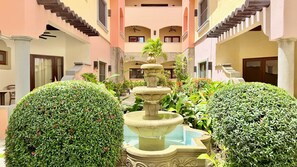 A courtyard with a central fountain, surrounded by neatly trimmed hedges and a multi-story building with balconies. - Mission Gate 5B @ West Bay (West Bay)