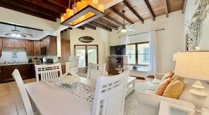 A spacious living area with a dining table, white furniture, a television, and a ceiling fan. - Mission Gate 5B @ West Bay (West Bay)