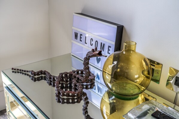 A reception desk with a 'WELCOME' sign, a decorative metal sculpture, and a golden vase. - Gorgeous Hampstead Flat (London)