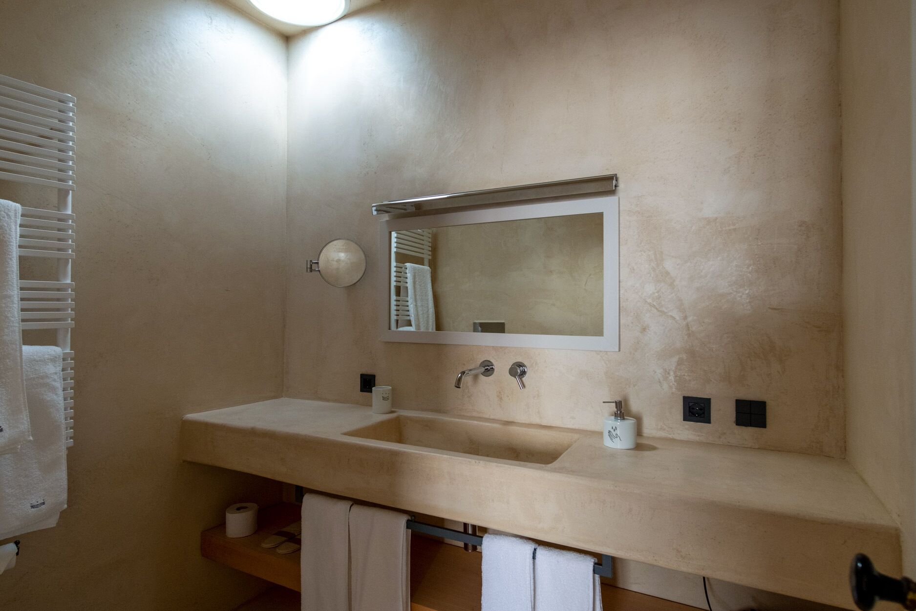 Un baño con un lavamanos color beige, un espejo y un perchero para toallas.
