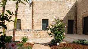 A courtyard with a stone wall, a pathway, and various plants. - I Tre Bacili (Spongano)