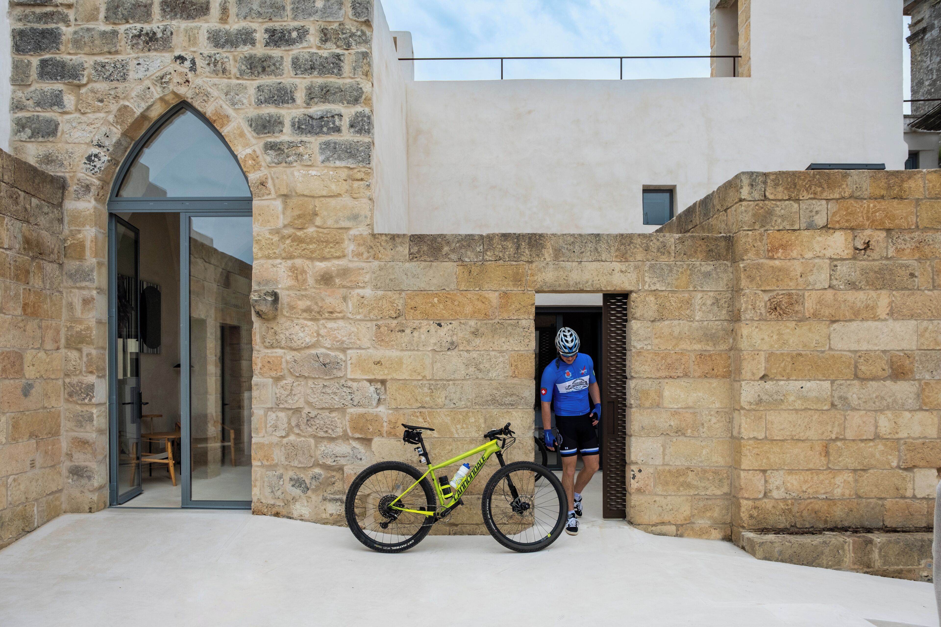 Ein Steinhaus mit einem großen Rundbogenportal und einem Fahrrad davor.