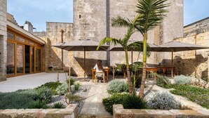 A courtyard with stone walls, outdoor seating, and a palm tree. - I Tre Bacili (Spongano)