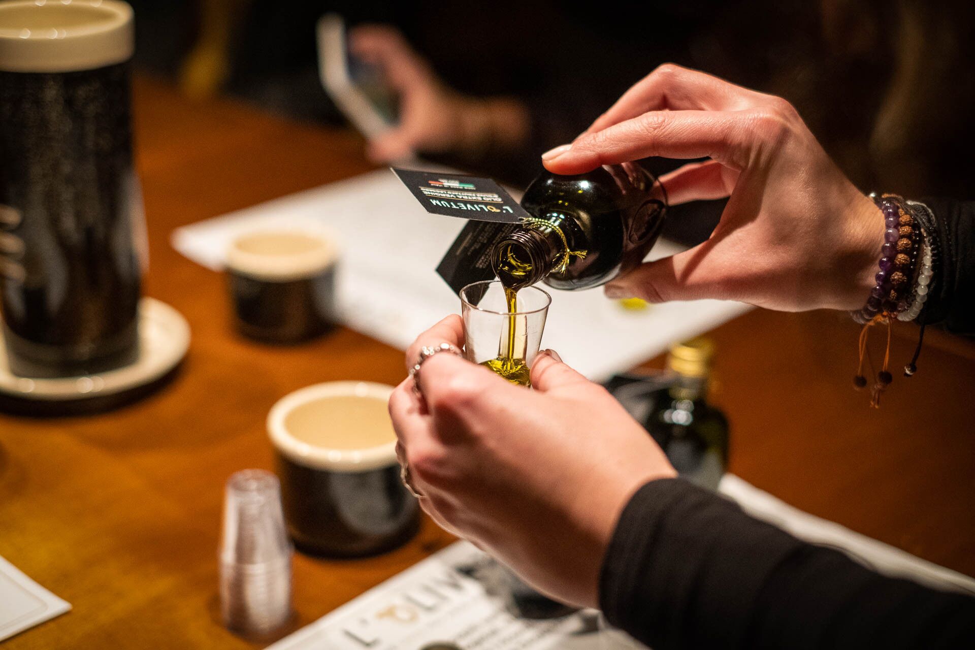 Iemand giet een donkere vloeistof uit een fles in een helder glas.