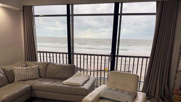 Un salón con un ventanal grande con vistas a una playa.