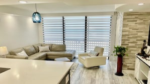 A modern living room with a sofa, armchair, and a dining area.