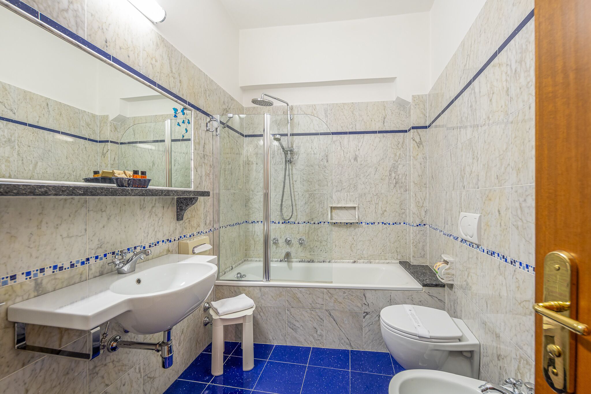 Un baño con ducha de vidrio, lavamanos blanco, inodoro y bidé.
