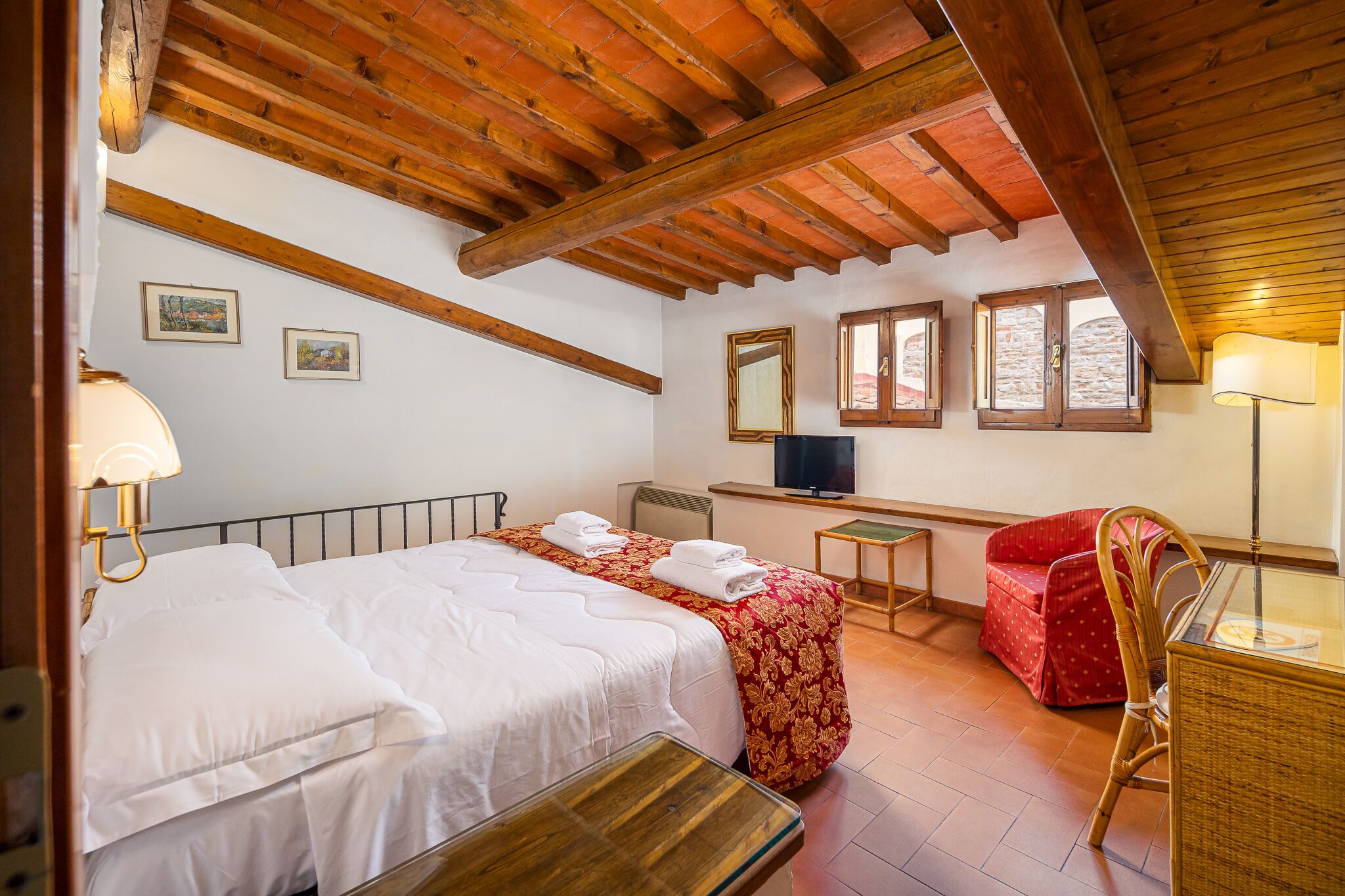A bedroom with two beds, a desk, a chair, and a television.
