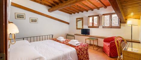 A bedroom with two beds, a desk, a chair, and a television.