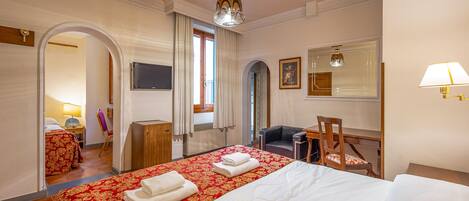 Ett hotellrum med en stor säng, ett skrivbord, en stol och en tv.