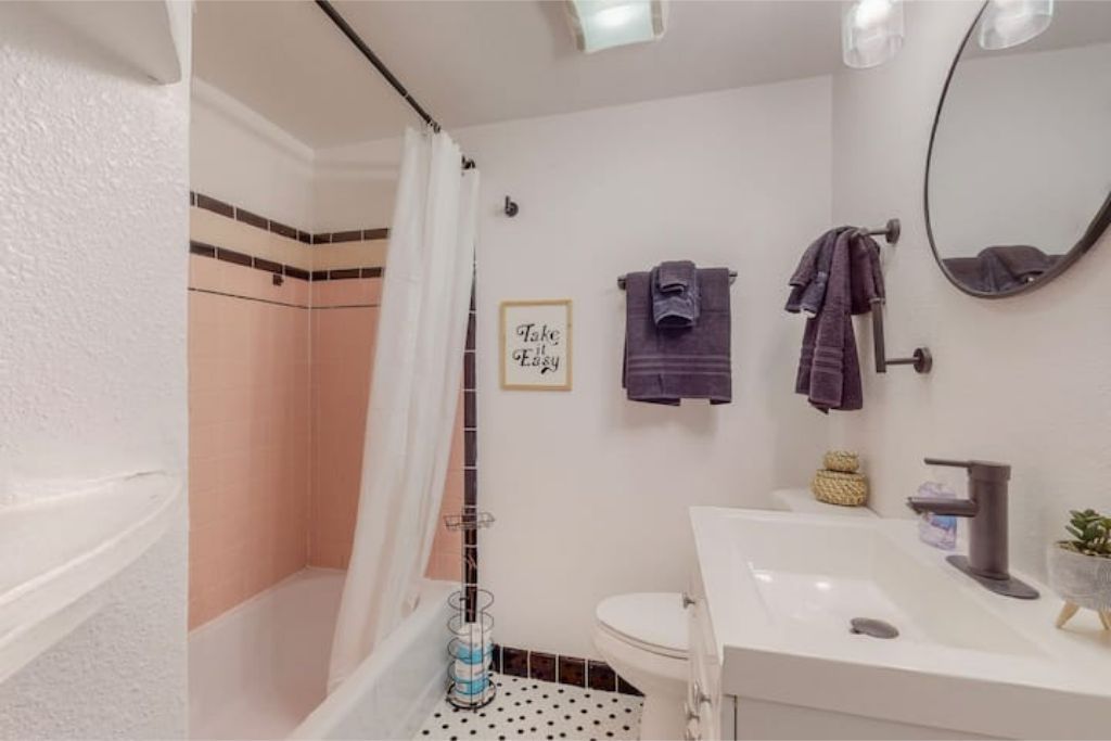 Een badkamer met douche, toilet, wastafel en spiegel.