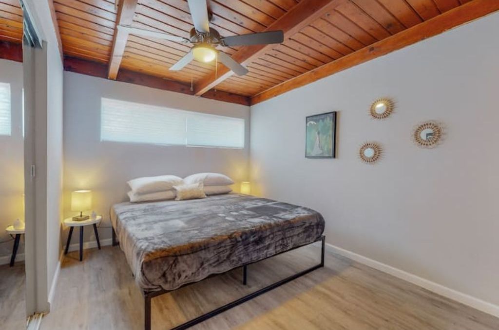 Une chambre à coucher avec un lit, un ventilateur de plafond, une fenêtre et des éléments de décoration murale.