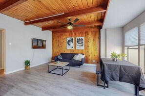 Relax in this inviting living area with a high ceiling, wooden paneling, and a comfortable sofa.