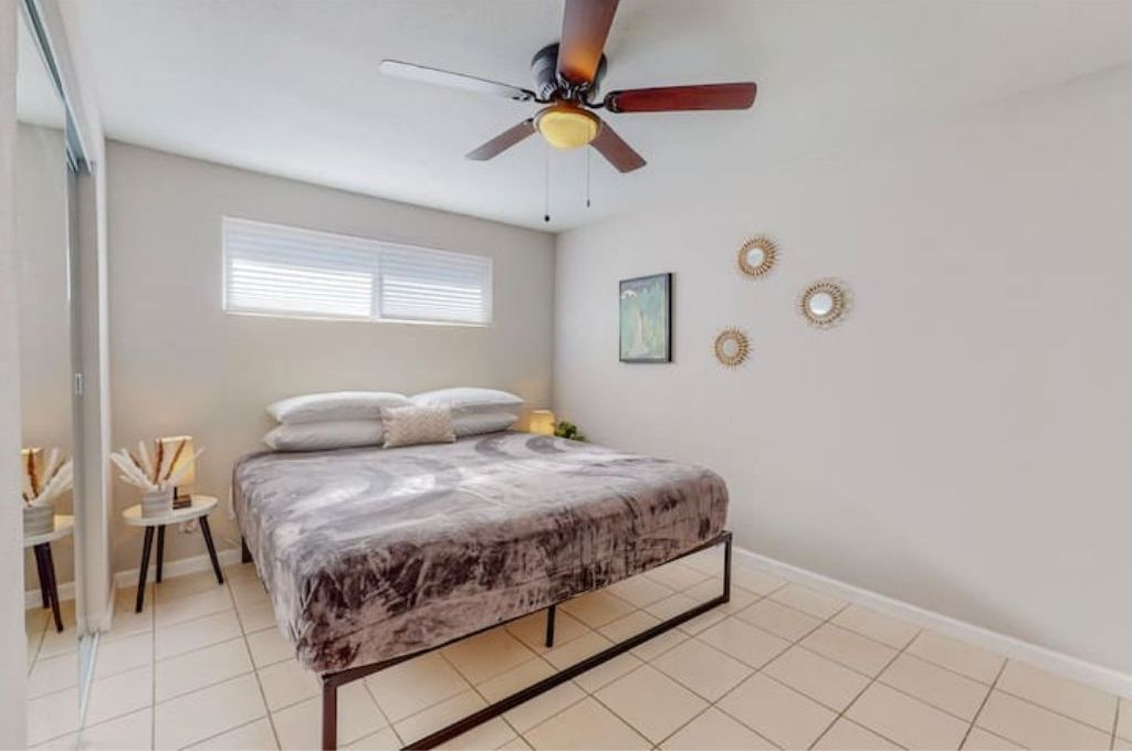 A bedroom with a bed, a ceiling fan, a window, and decorative wall art.