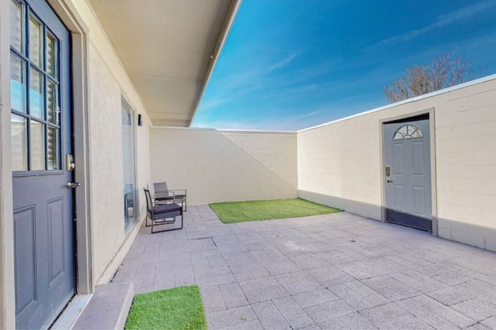 Un espacio exterior techado con un patio, una puerta y una pequeña zona de estar.