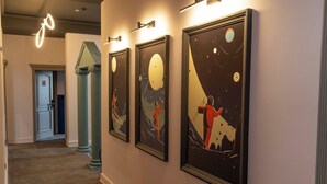 A hallway with framed artwork depicting space scenes, a door, and a staircase. - Maria Luisa by INTROVERT HOTELS (Sofia)