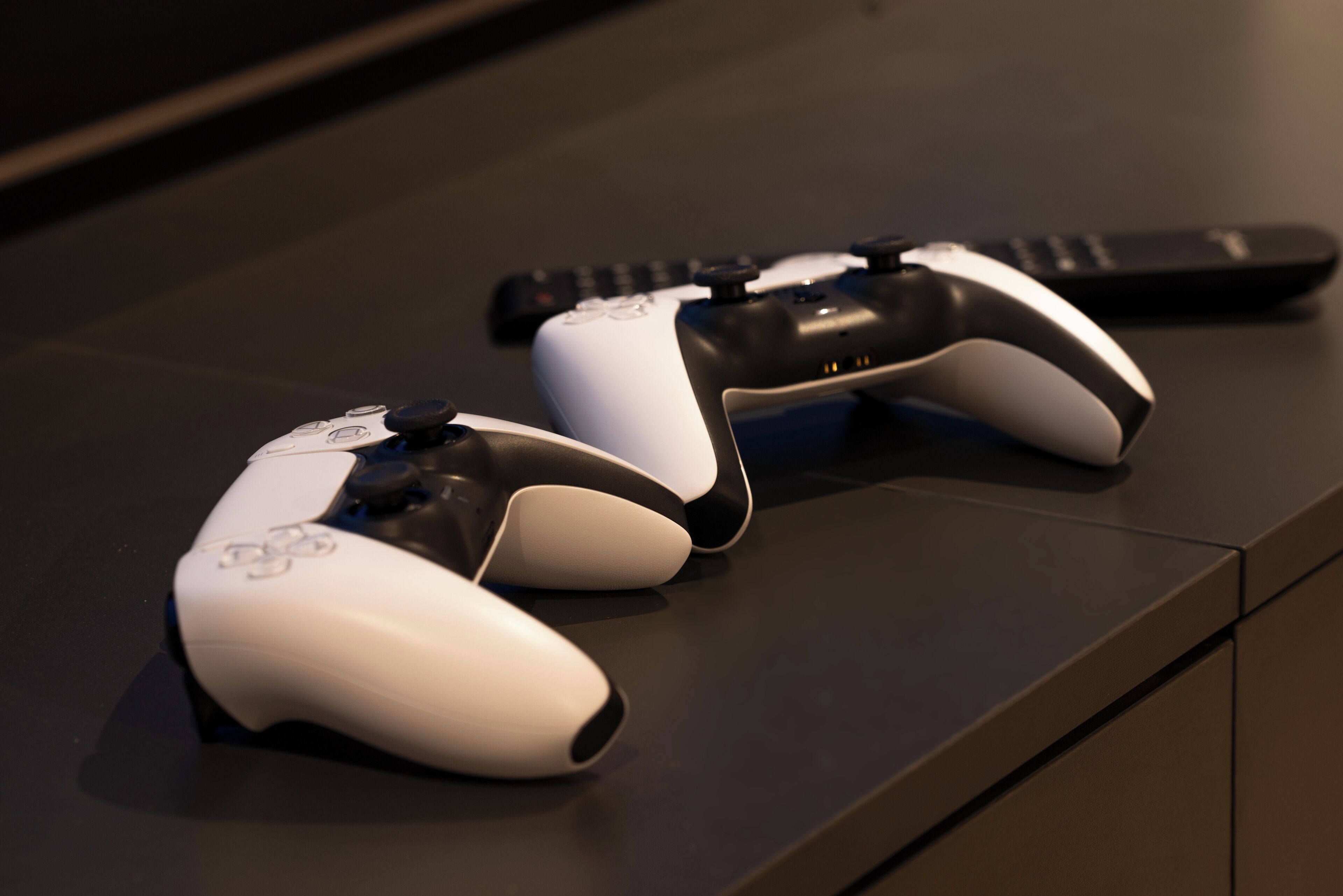 Dos controles de juego blancos y negros sobre una superficie oscura.