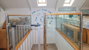 Quarto tipo loft moderno com claraboias, guarda-corpo de vidro e um mural na parede.