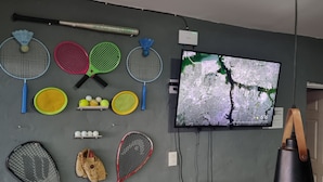 A room with a wall-mounted TV displaying a city map, various badminton rackets, and a tennis racket. - Casa de Playa con Mini Golf (La Libertad Department)